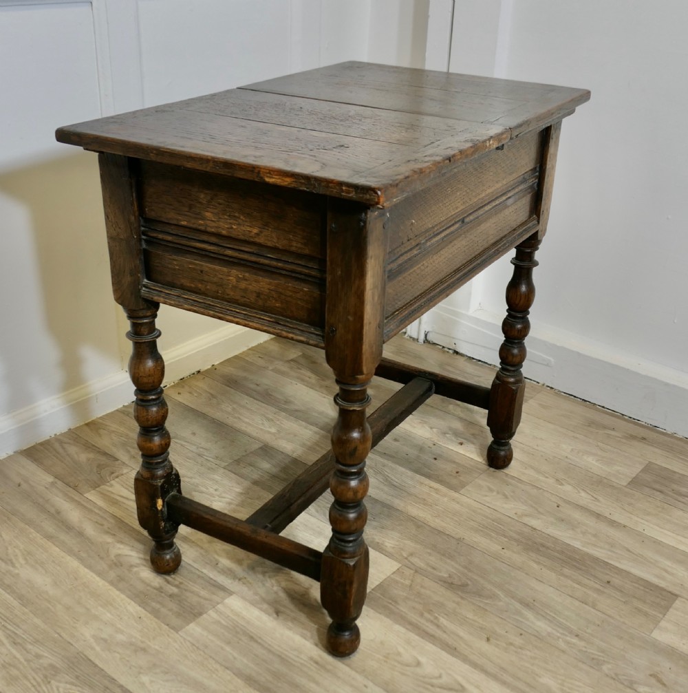A dark oak joint stool featuring a rectangular plank top, a moulded frieze, turned legs, and a low perimeter stretcher base. View III