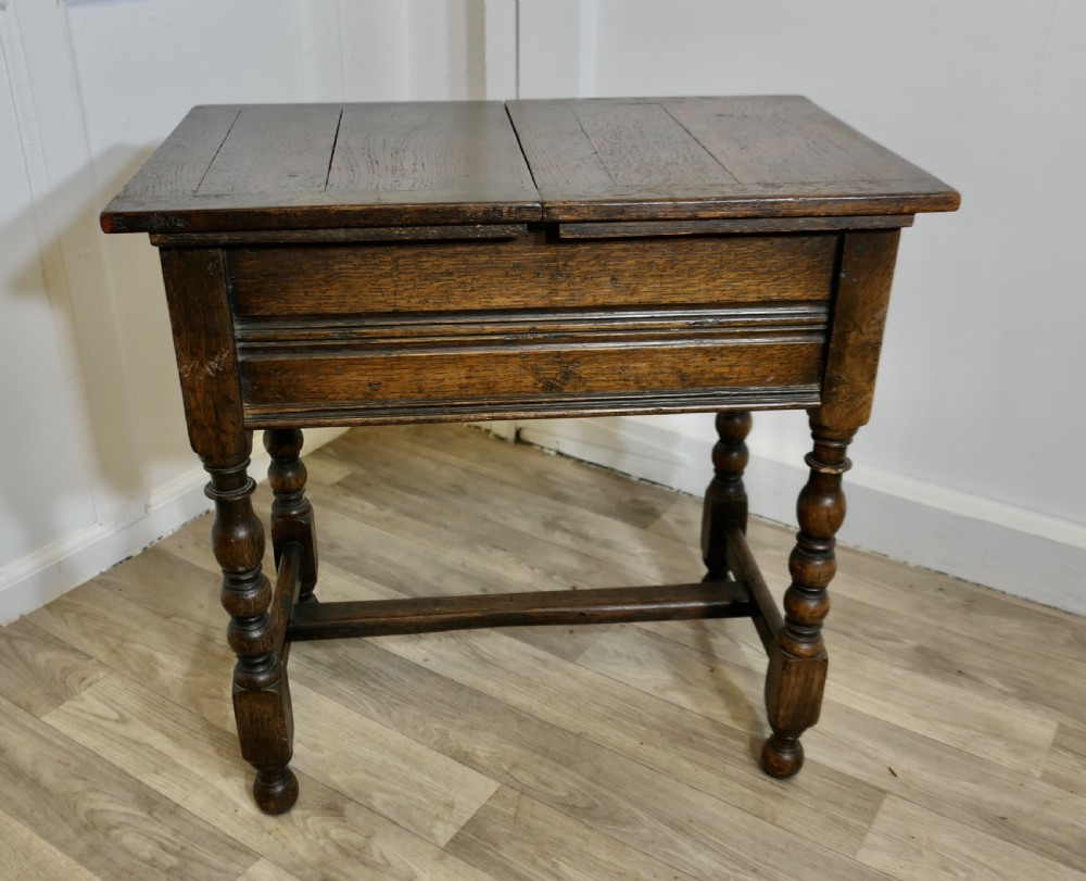 A dark oak joint stool featuring a rectangular plank top, a moulded frieze, turned legs, and a low perimeter stretcher base. View V