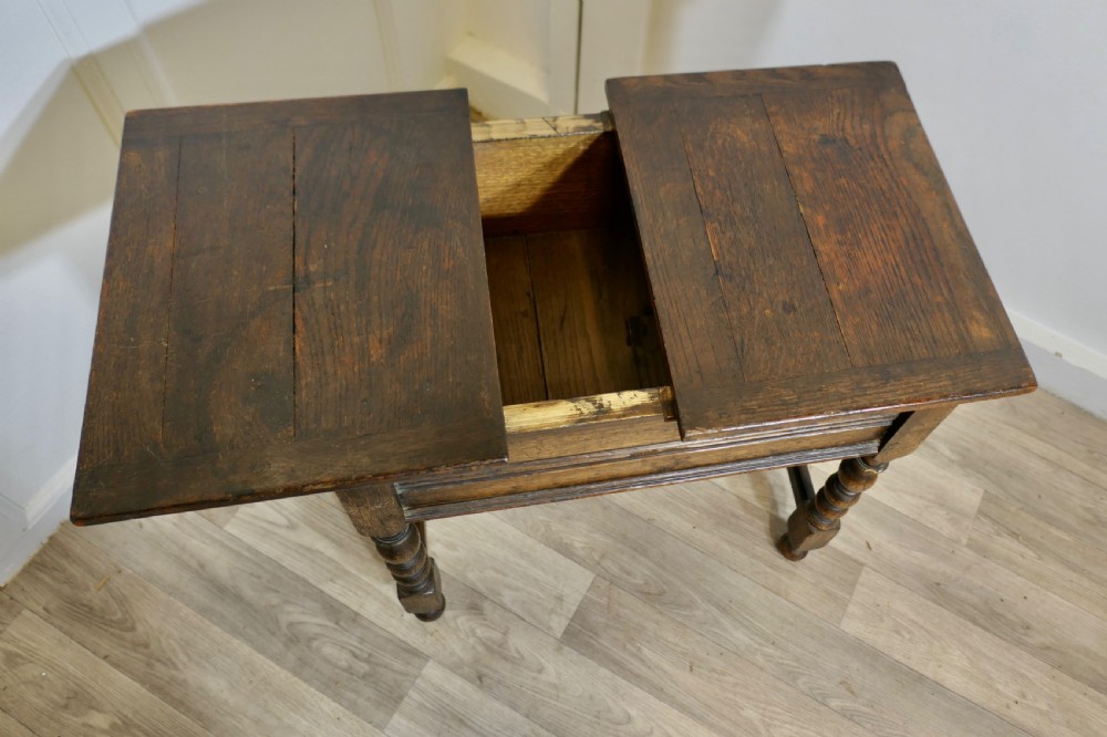 A dark oak joint stool featuring a rectangular plank top, a moulded frieze, turned legs, and a low perimeter stretcher base. View VI