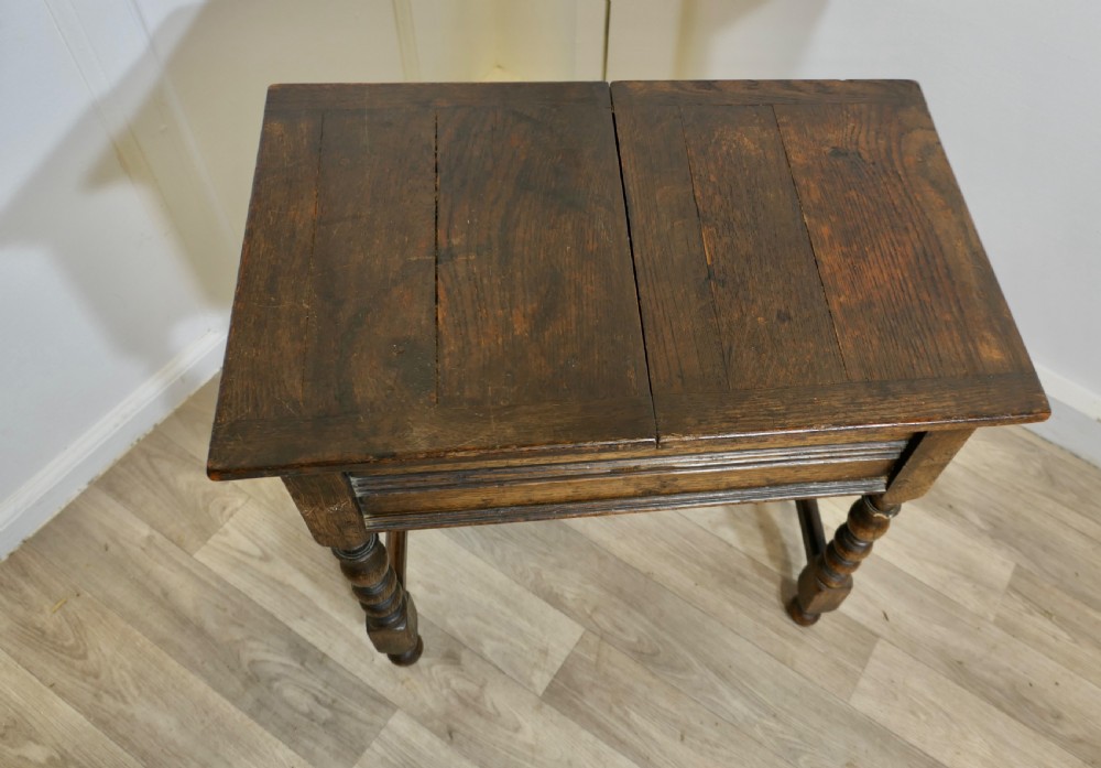 A dark oak joint stool featuring a rectangular plank top, a moulded frieze, turned legs, and a low perimeter stretcher base. View VII