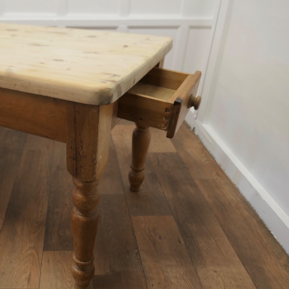 A rectangular pine kitchen table with a scrubbed natural wood top, turned legs, and a single drawer with a wooden knob pull. View II