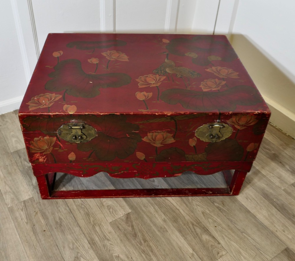 A red painted Chinoiserie marriage chest decorated with lotus motifs, raised on a low timber stand with brass clasps. View II