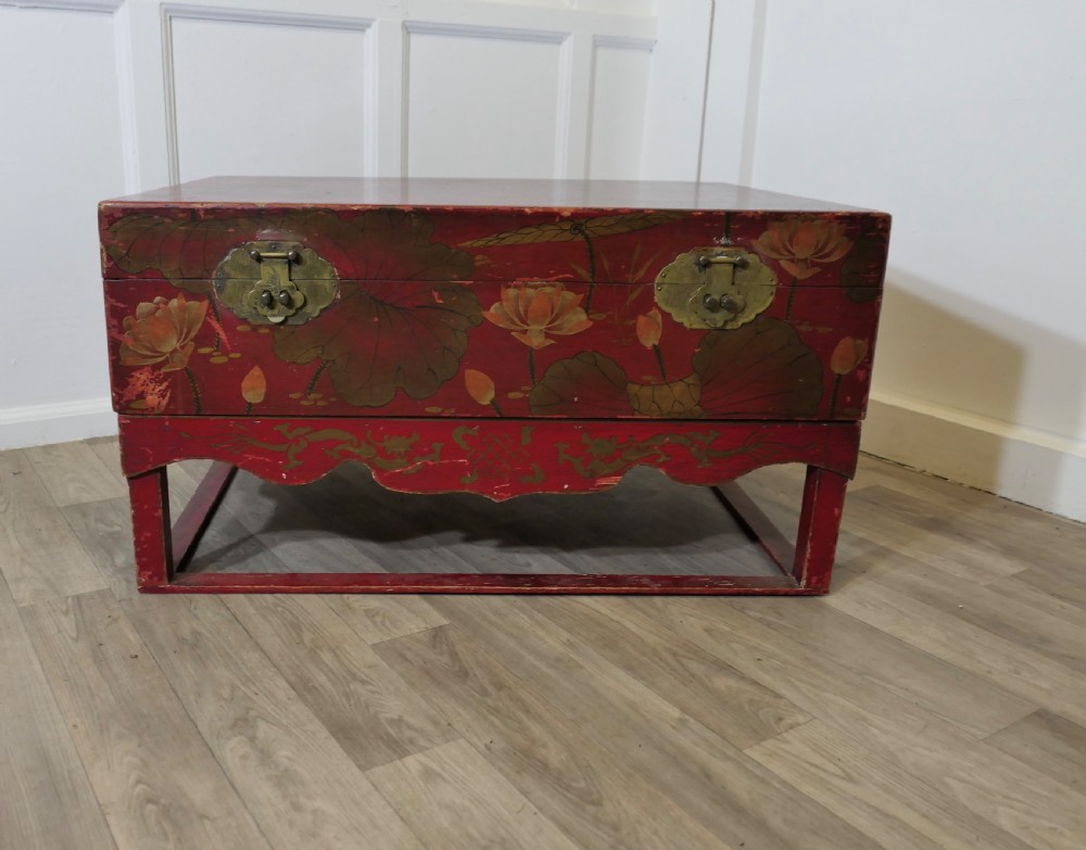 A red painted Chinoiserie marriage chest decorated with lotus motifs, raised on a low timber stand with brass clasps. View III