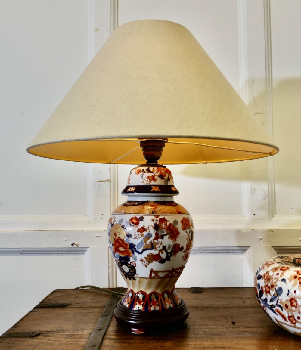 A Japanese Imari porcelain vase converted into a table lamp with a cream conical shade, positioned beside a matching decorated lidded bowl. View III