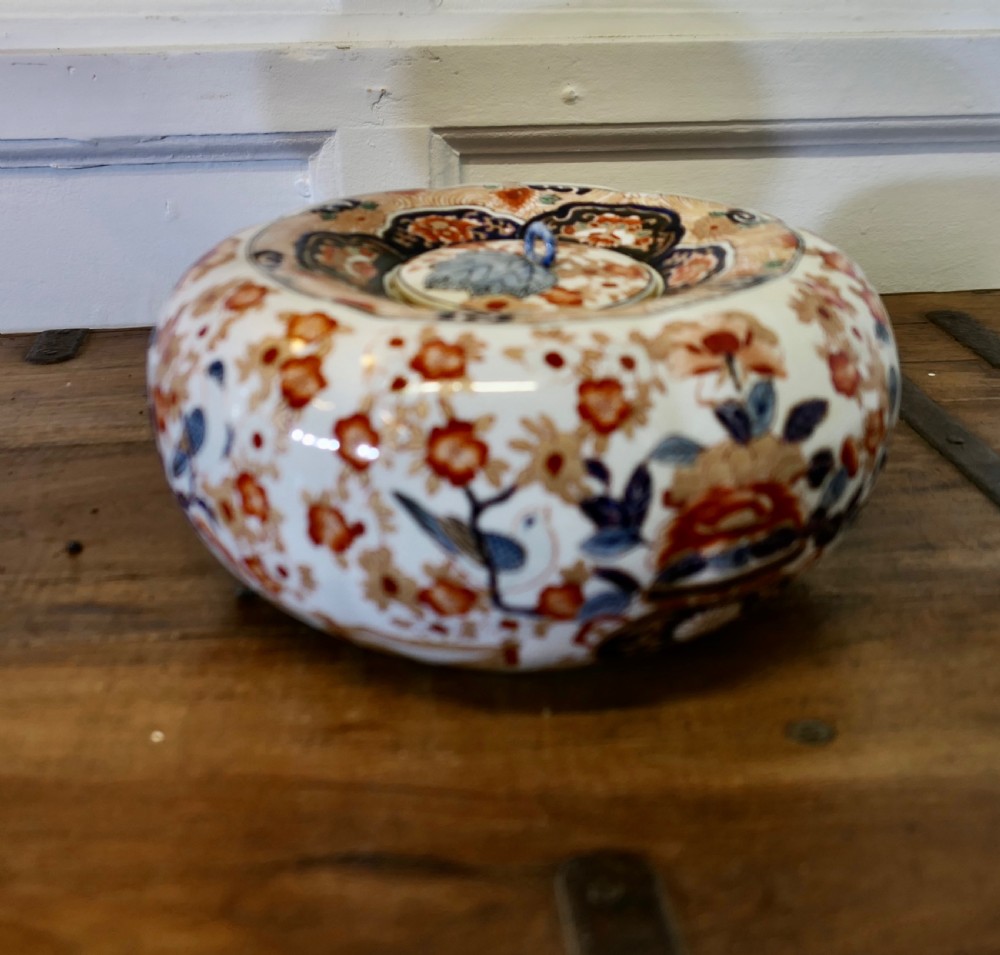 A Japanese Imari porcelain vase converted into a table lamp with a cream conical shade, positioned beside a matching decorated lidded bowl. View VII