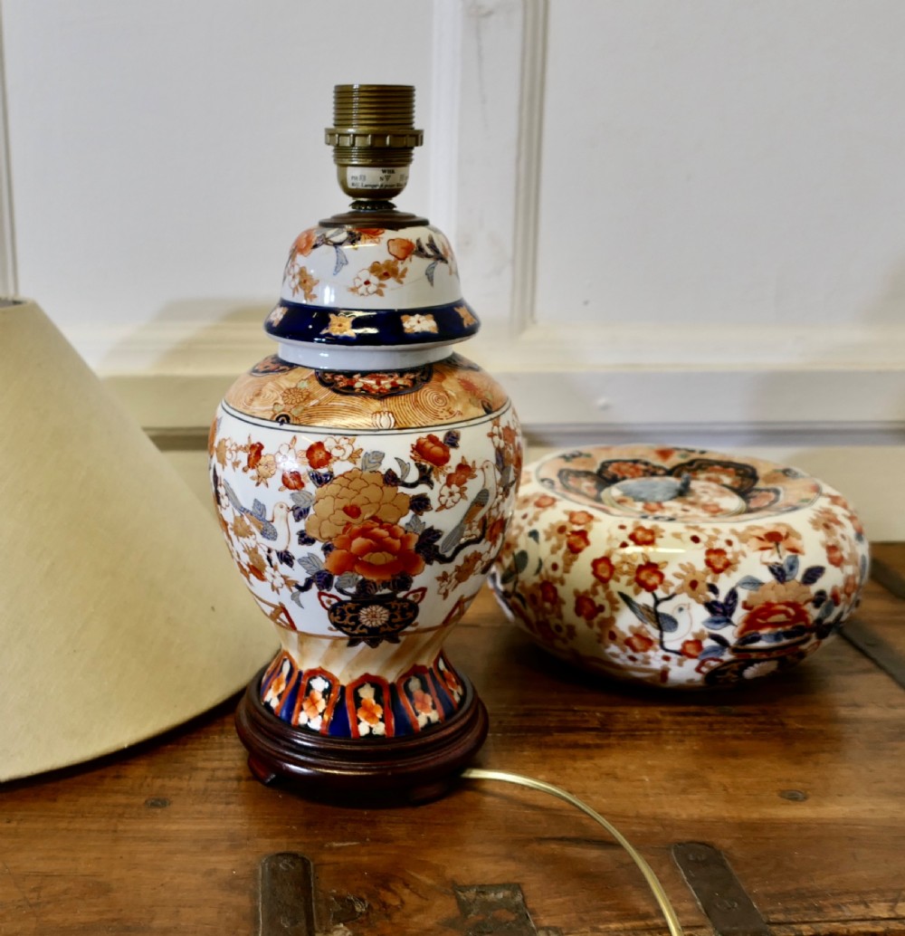 A Japanese Imari porcelain vase converted into a table lamp with a cream conical shade, positioned beside a matching decorated lidded bowl. View IX