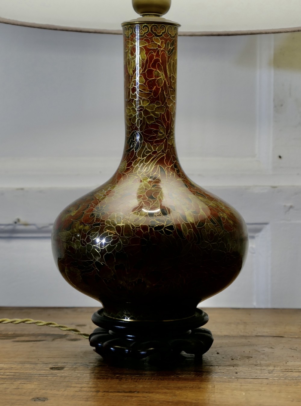 A baluster-shaped cloisonne table lamp featuring floral enamelling and a carved dark wood stand under a textured brown fabric lampshade. View III