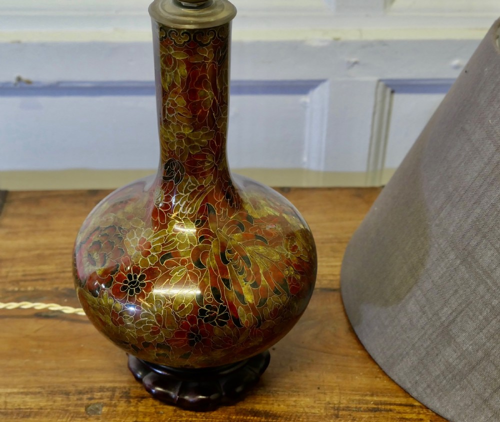 A baluster-shaped cloisonne table lamp featuring floral enamelling and a carved dark wood stand under a textured brown fabric lampshade. View V
