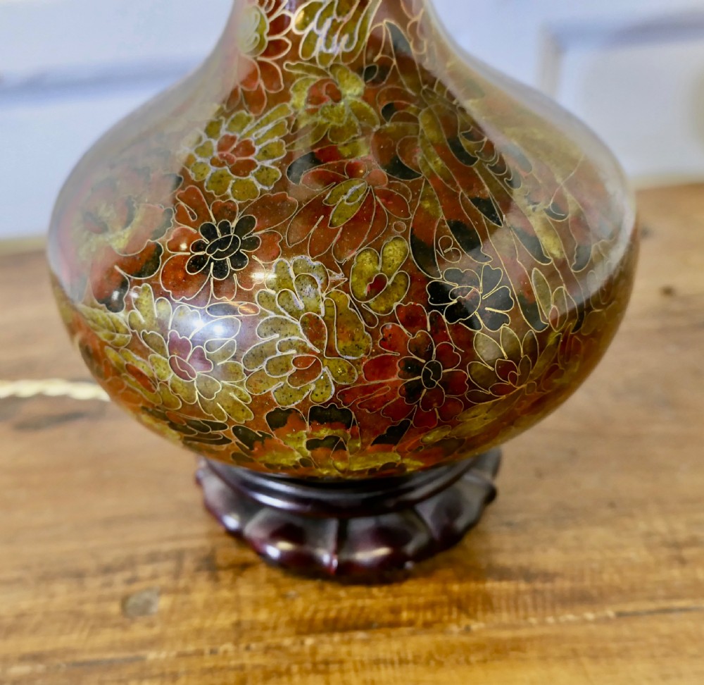A baluster-shaped cloisonne table lamp featuring floral enamelling and a carved dark wood stand under a textured brown fabric lampshade. View VII
