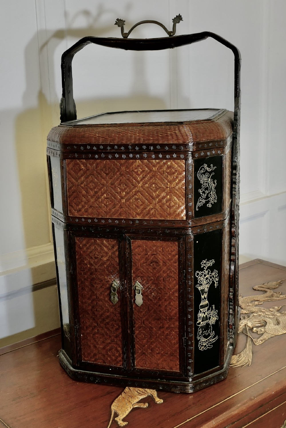 An octagonal Chinese wedding basket constructed from woven bamboo and dark lacquered wood with a tall overhead handle and double doors at the base.