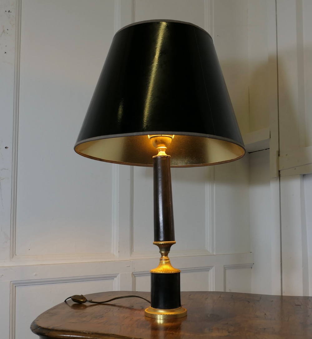 An Art Deco table lamp featuring a tapered black leather stem, a black conical shade, and turned brass fittings. View II