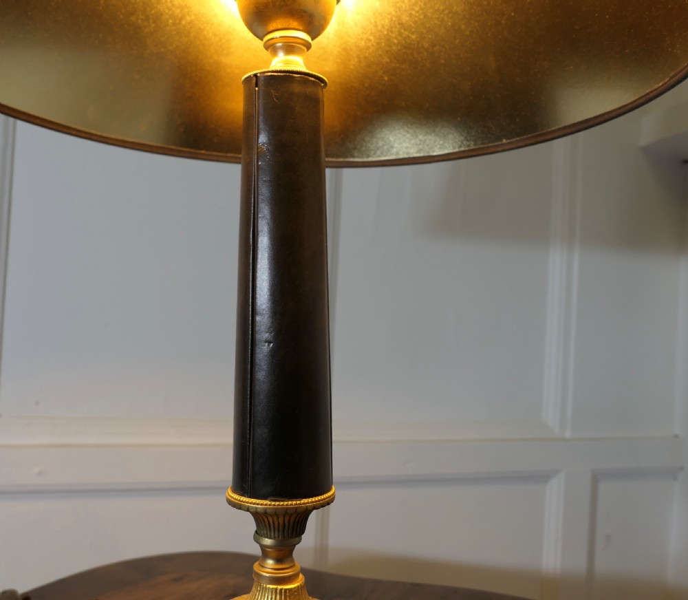 An Art Deco table lamp featuring a tapered black leather stem, a black conical shade, and turned brass fittings. View V