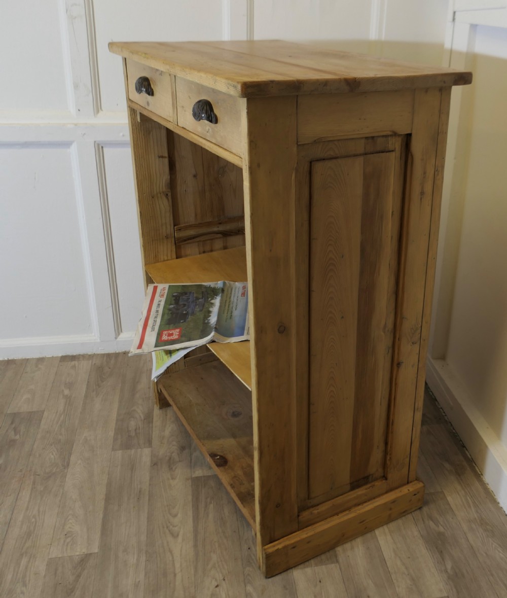 A tall standing pine desk featuring two upper drawers with dark metal cup handles above open lower shelving and panelled sides.