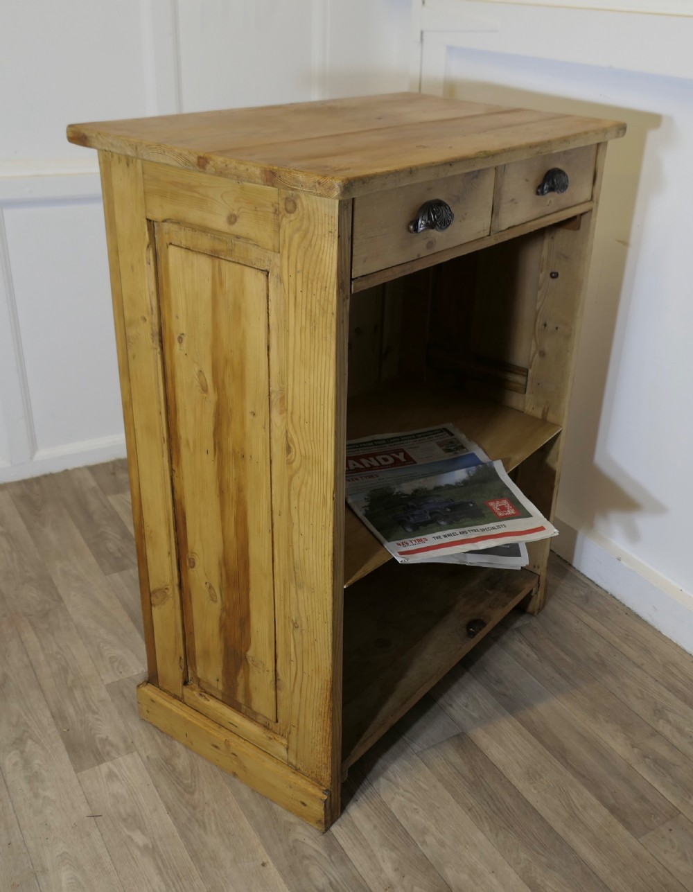 A tall standing pine desk featuring two upper drawers with dark metal cup handles above open lower shelving and panelled sides. View III