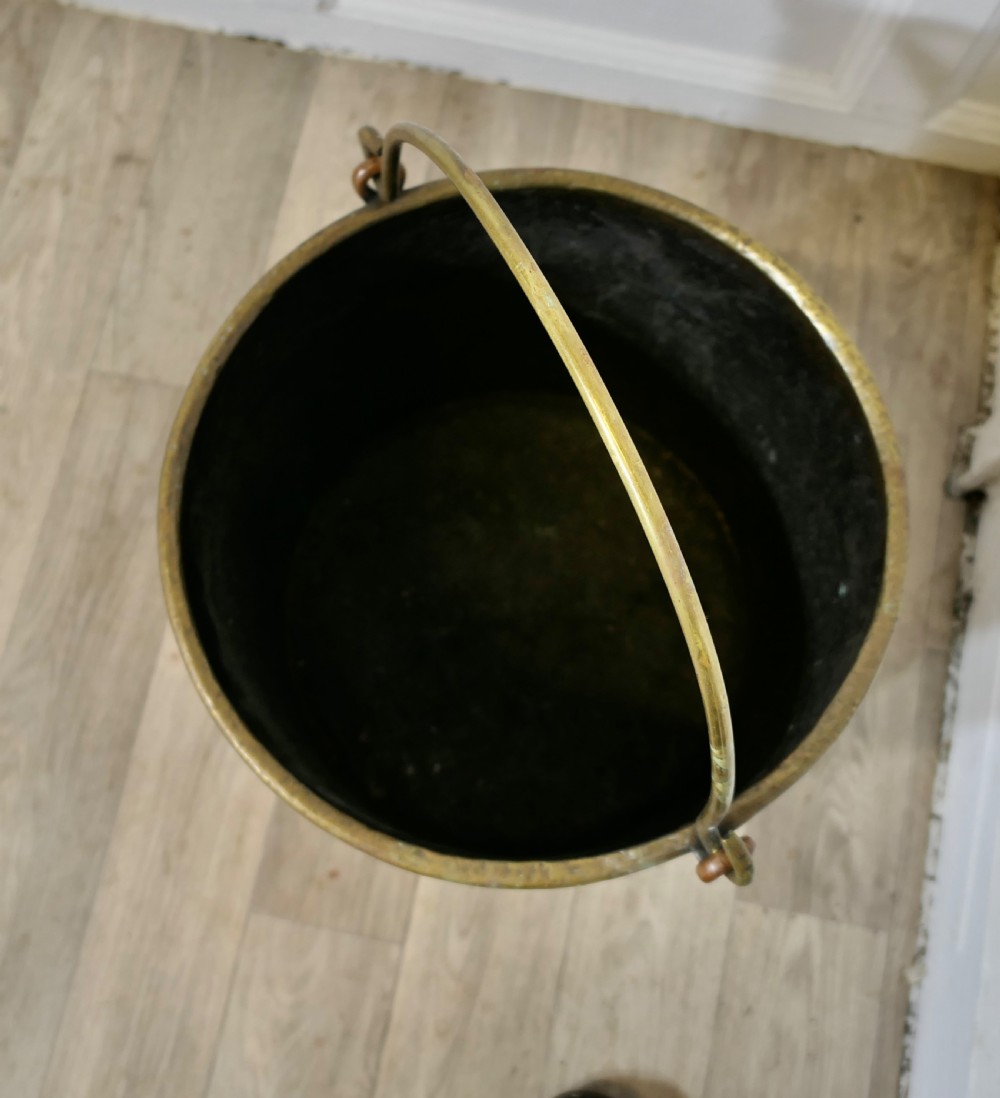 A cylindrical hand-hammered copper bucket featuring a wide brass top collar, riveted seam, and a curved brass swing handle. View XII