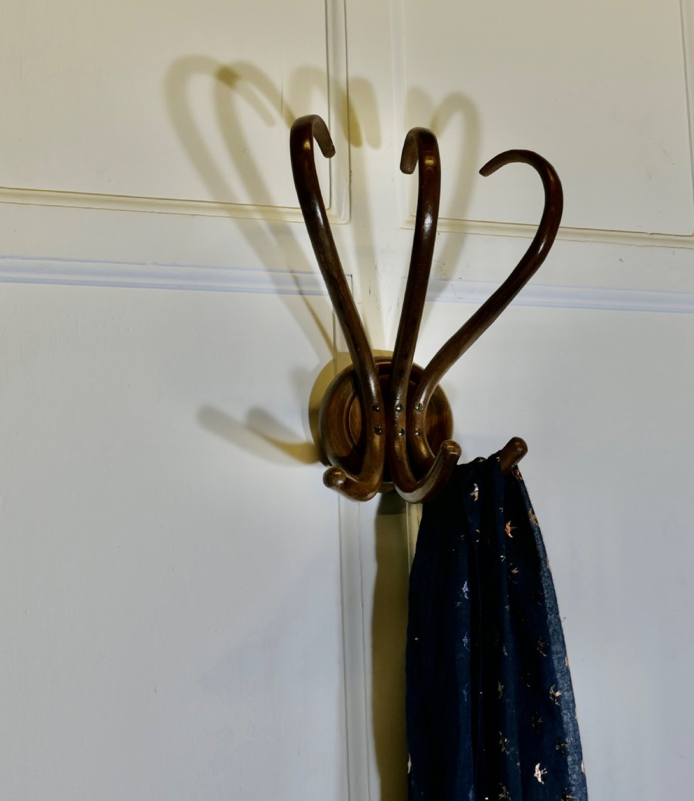 A dark brown bentwood wall-mounted coat rack featuring three sweeping upper hooks and three smaller lower hooks attached to a central circular base. View VI