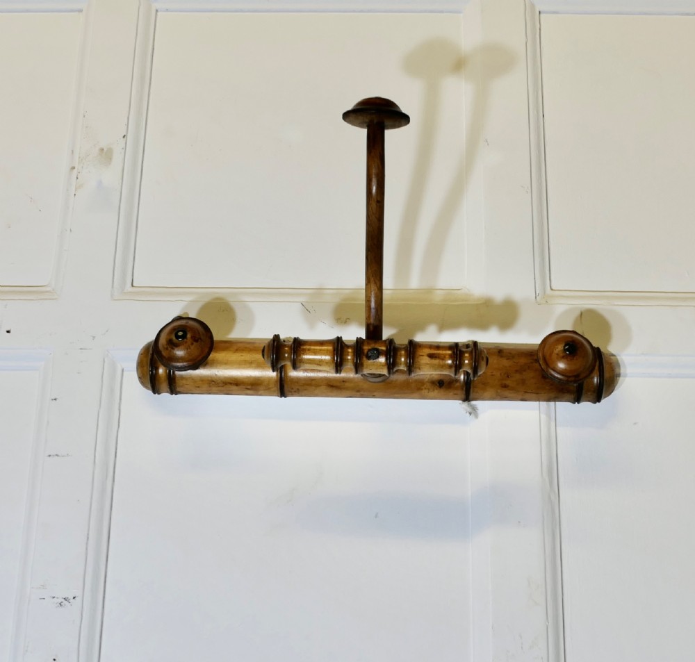 An antique French wall-mounted coat rack crafted from turned wood carved in a simulated bamboo design with turned hanging pegs.