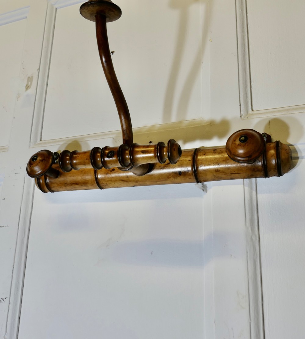 An antique French wall-mounted coat rack crafted from turned wood carved in a simulated bamboo design with turned hanging pegs. View II