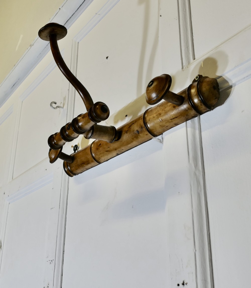An antique French wall-mounted coat rack crafted from turned wood carved in a simulated bamboo design with turned hanging pegs. View V