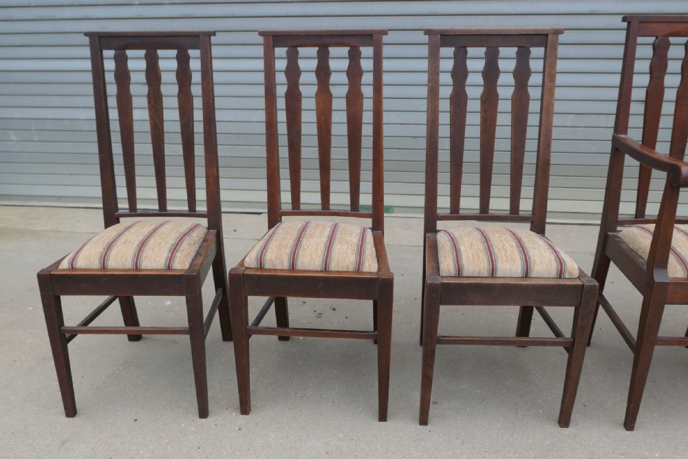 A set of six dark oak Arts and Crafts dining chairs featuring high vertical slat backs and striped fabric drop-in seats. View III