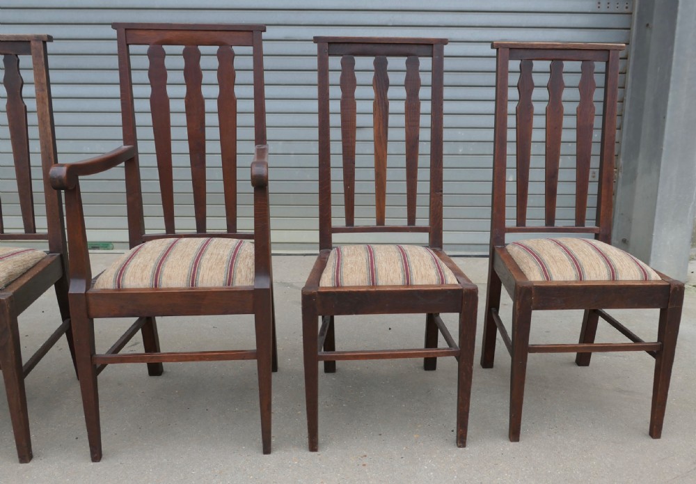 A set of six dark oak Arts and Crafts dining chairs featuring high vertical slat backs and striped fabric drop-in seats. View IV