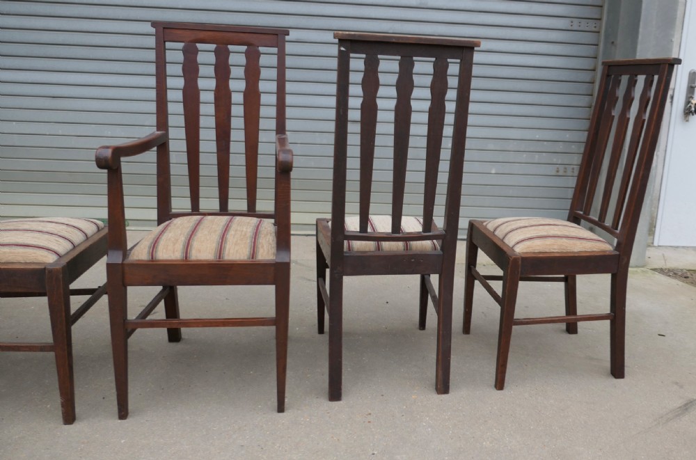 A set of six dark oak Arts and Crafts dining chairs featuring high vertical slat backs and striped fabric drop-in seats. View V