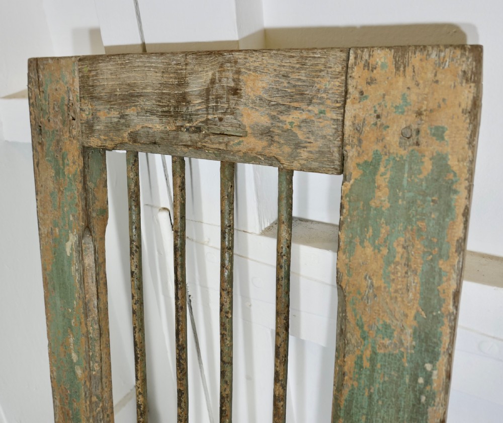 A pair of tall, rectangular antique wooden window shutters with vertical wrought iron bars and weathered green and ochre paint finish. View VI