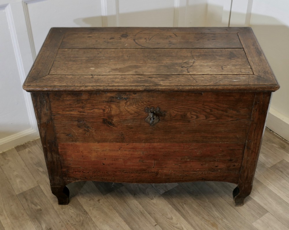An 18th-century small dark oak French coffer featuring a flat top, central wrought iron escutcheon, and subtle cabriole legs. View II