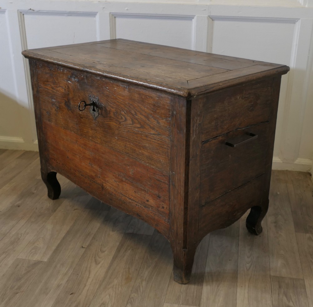 An 18th-century small dark oak French coffer featuring a flat top, central wrought iron escutcheon, and subtle cabriole legs. View III