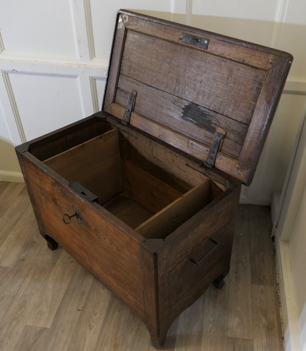 An 18th-century small dark oak French coffer featuring a flat top, central wrought iron escutcheon, and subtle cabriole legs. View V