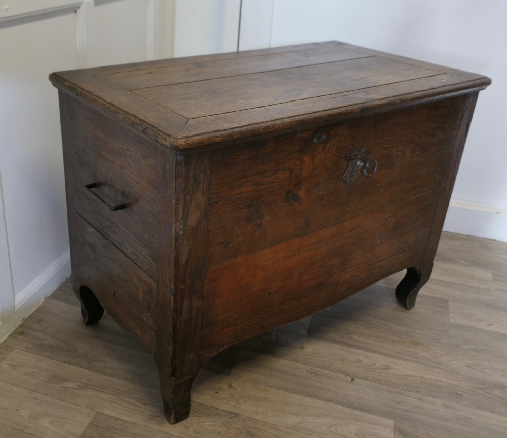An 18th-century small dark oak French coffer featuring a flat top, central wrought iron escutcheon, and subtle cabriole legs. View VI