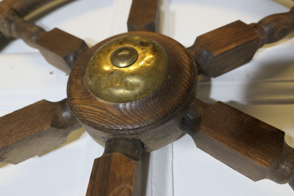 An early twentieth-century oak ship wheel featuring eight turned spokes and a central brass hub. View II