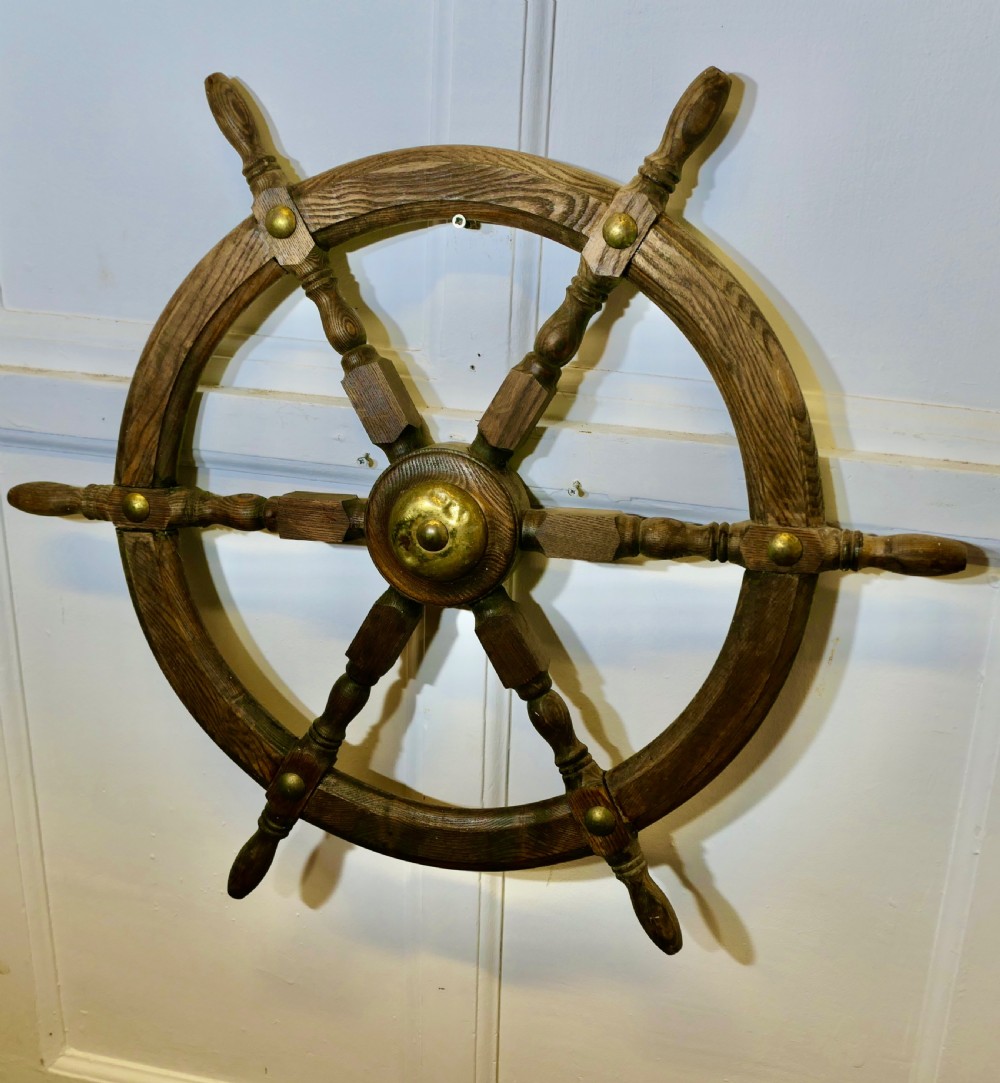 An early twentieth-century oak ship wheel featuring eight turned spokes and a central brass hub. View III