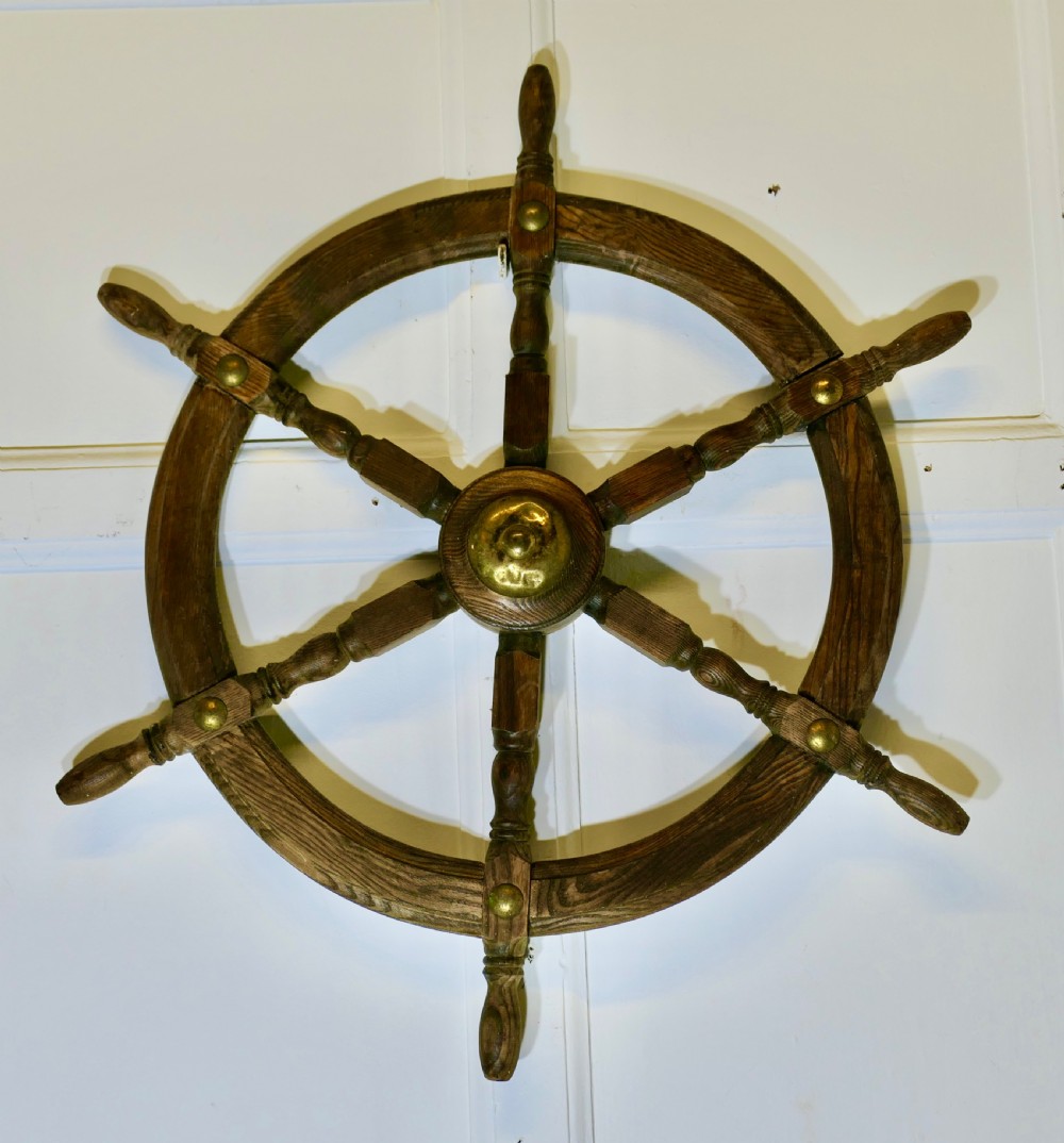 An early twentieth-century oak ship wheel featuring eight turned spokes and a central brass hub. View IV