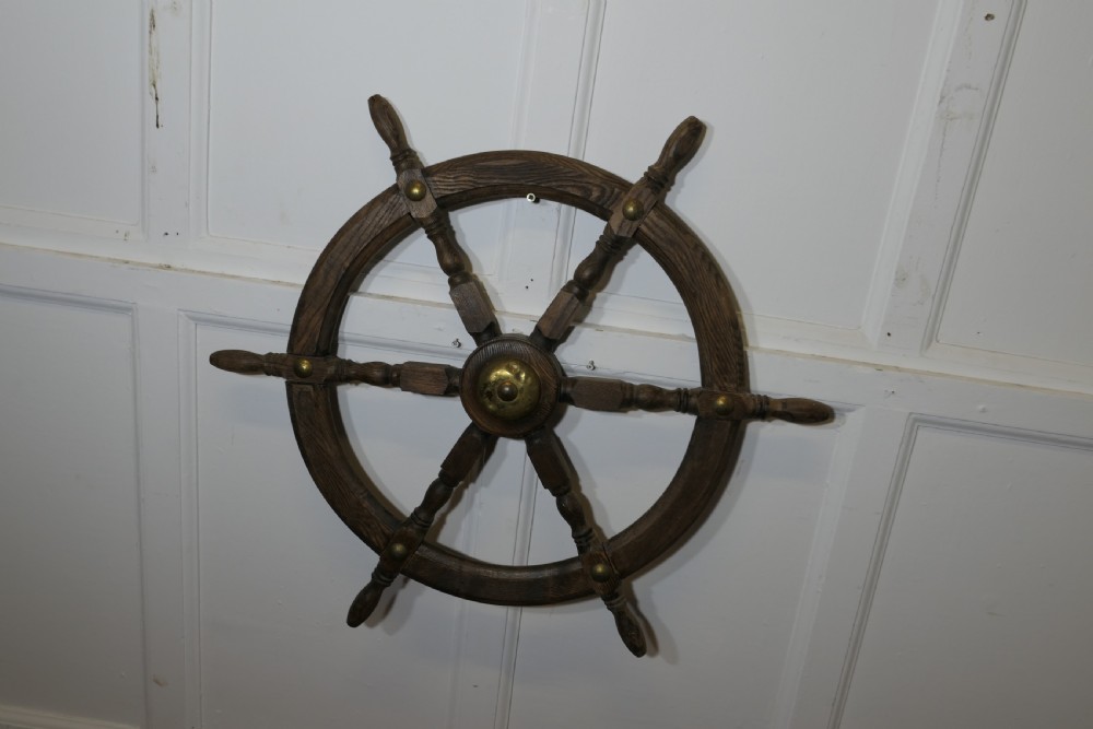 An early twentieth-century oak ship wheel featuring eight turned spokes and a central brass hub. View V