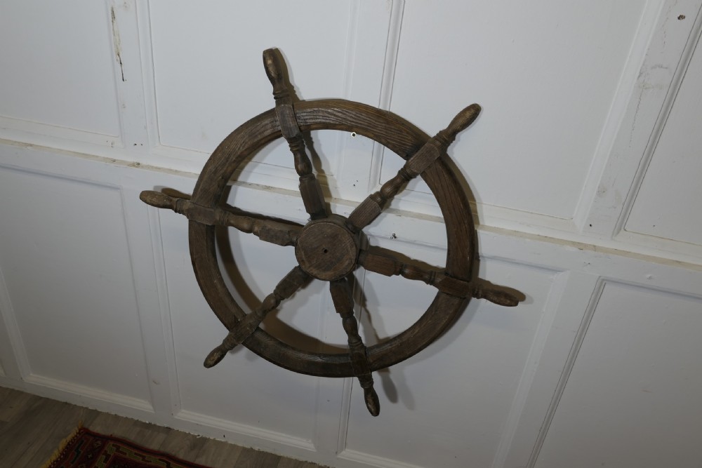 An early twentieth-century oak ship wheel featuring eight turned spokes and a central brass hub. View VI