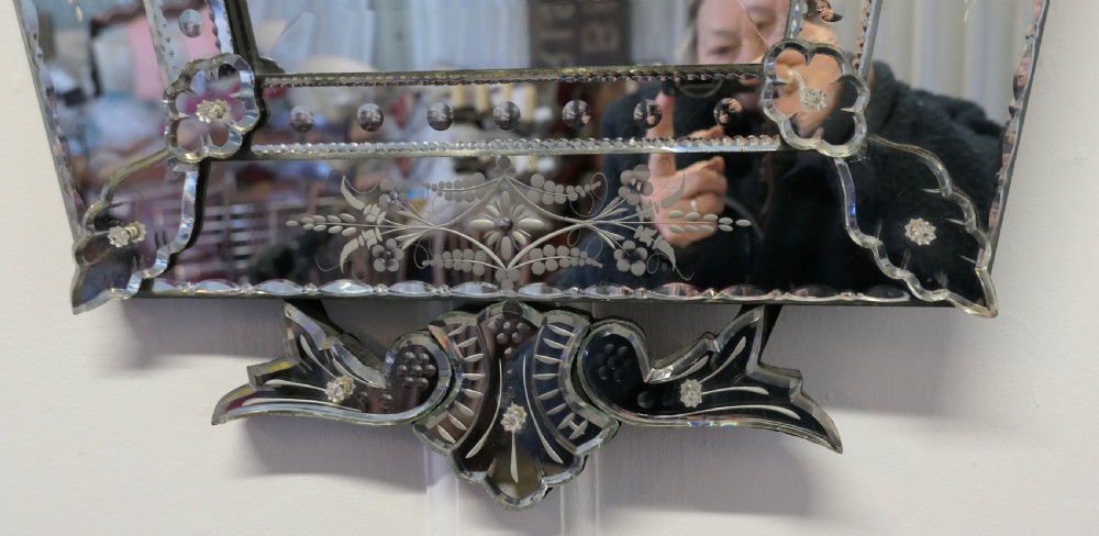 A Venetian cushion wall mirror with an etched floral glass frame, a carved glass crest pediment, and an arched central mirror plate. View VII