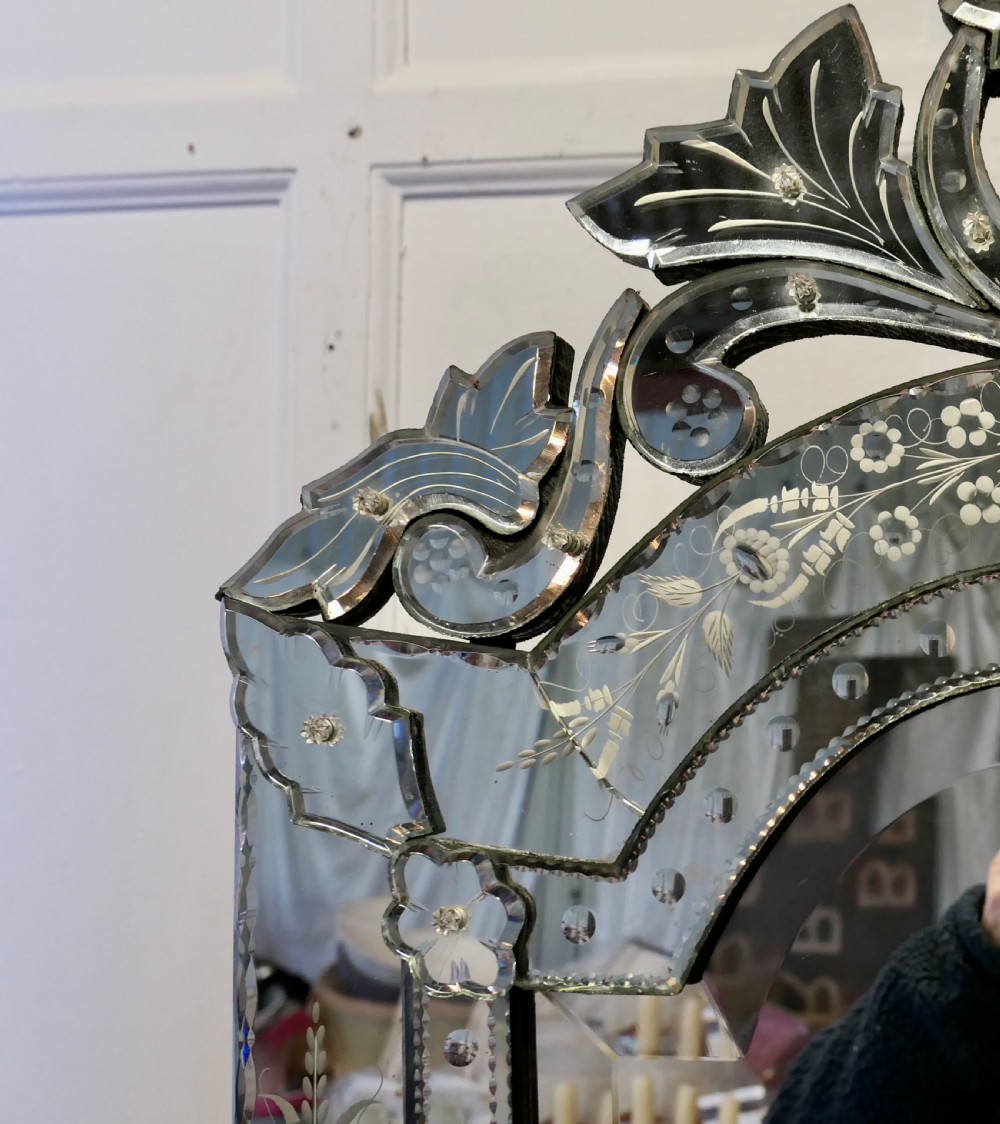 A Venetian cushion wall mirror with an etched floral glass frame, a carved glass crest pediment, and an arched central mirror plate. View IX