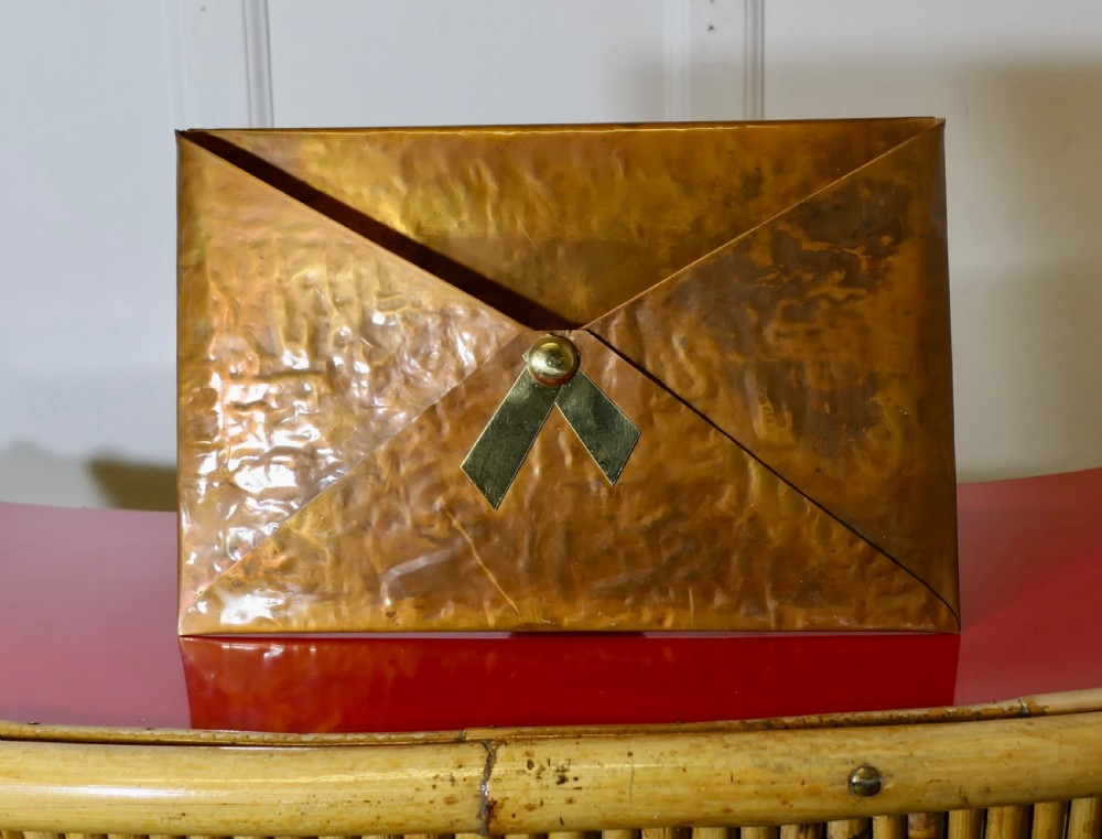 A hammered copper letter rack fashioned in the shape of an envelope, featuring a brass rivet and clasp detail.