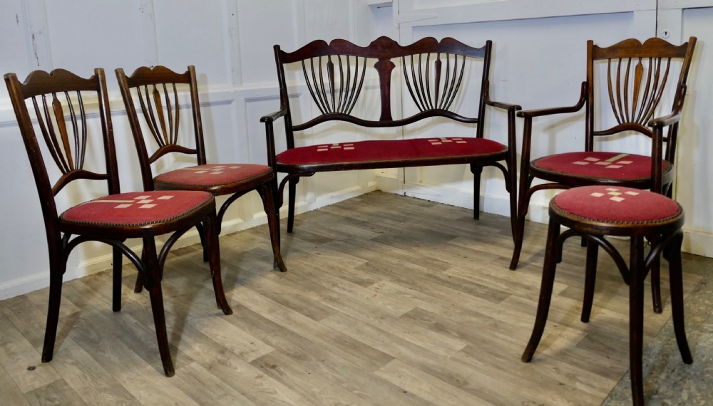 A five-piece dark bentwood salon suite comprising a two-seater settee, two side chairs, an armchair, and a circular stool with red upholstered seats.
