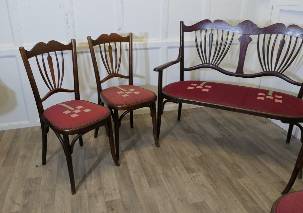 A five-piece dark bentwood salon suite comprising a two-seater settee, two side chairs, an armchair, and a circular stool with red upholstered seats. View III