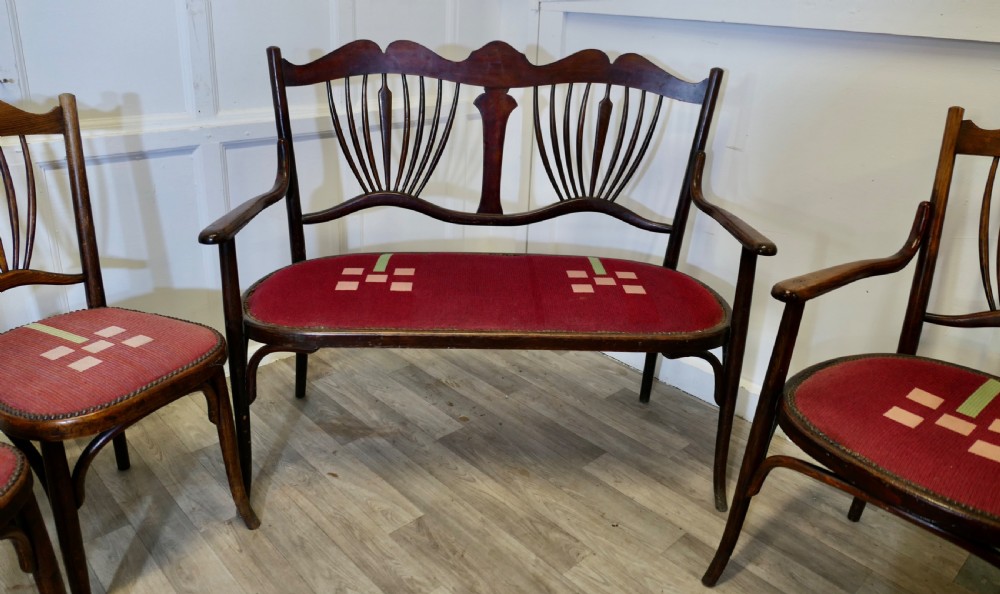 A five-piece dark bentwood salon suite comprising a two-seater settee, two side chairs, an armchair, and a circular stool with red upholstered seats. View V