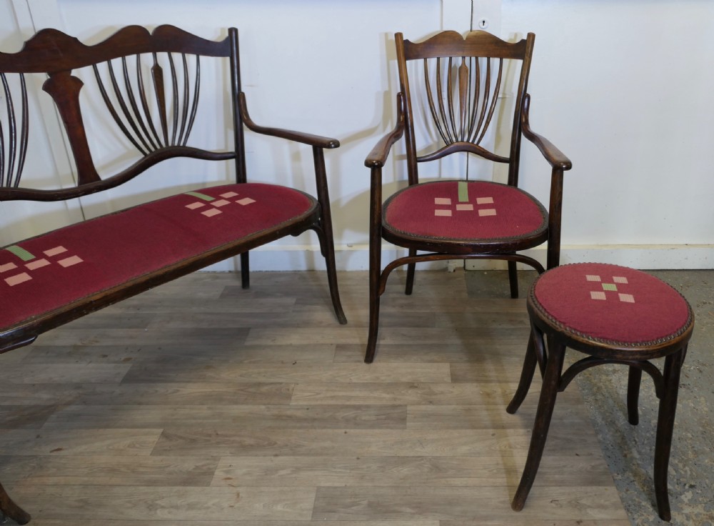 A five-piece dark bentwood salon suite comprising a two-seater settee, two side chairs, an armchair, and a circular stool with red upholstered seats. View VI