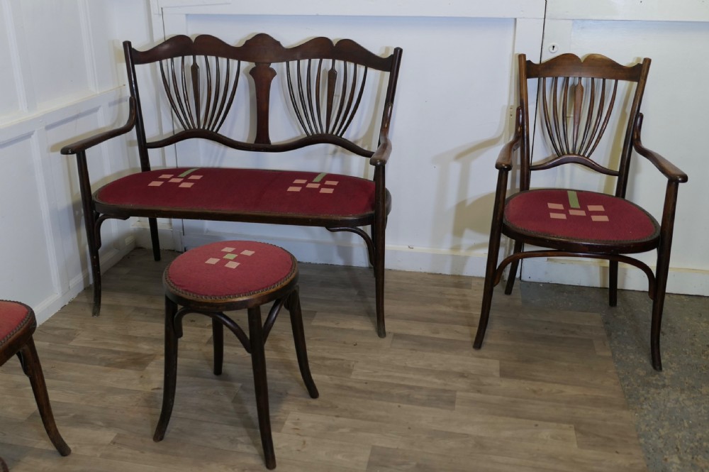 A five-piece dark bentwood salon suite comprising a two-seater settee, two side chairs, an armchair, and a circular stool with red upholstered seats. View VII