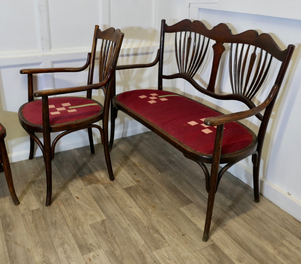 A five-piece dark bentwood salon suite comprising a two-seater settee, two side chairs, an armchair, and a circular stool with red upholstered seats. View VIII