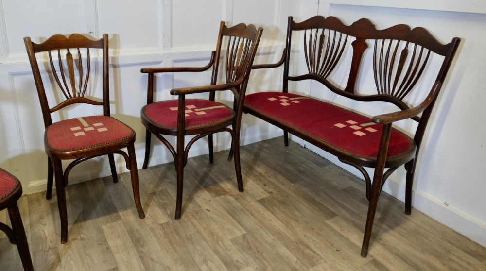 A five-piece dark bentwood salon suite comprising a two-seater settee, two side chairs, an armchair, and a circular stool with red upholstered seats. View IX