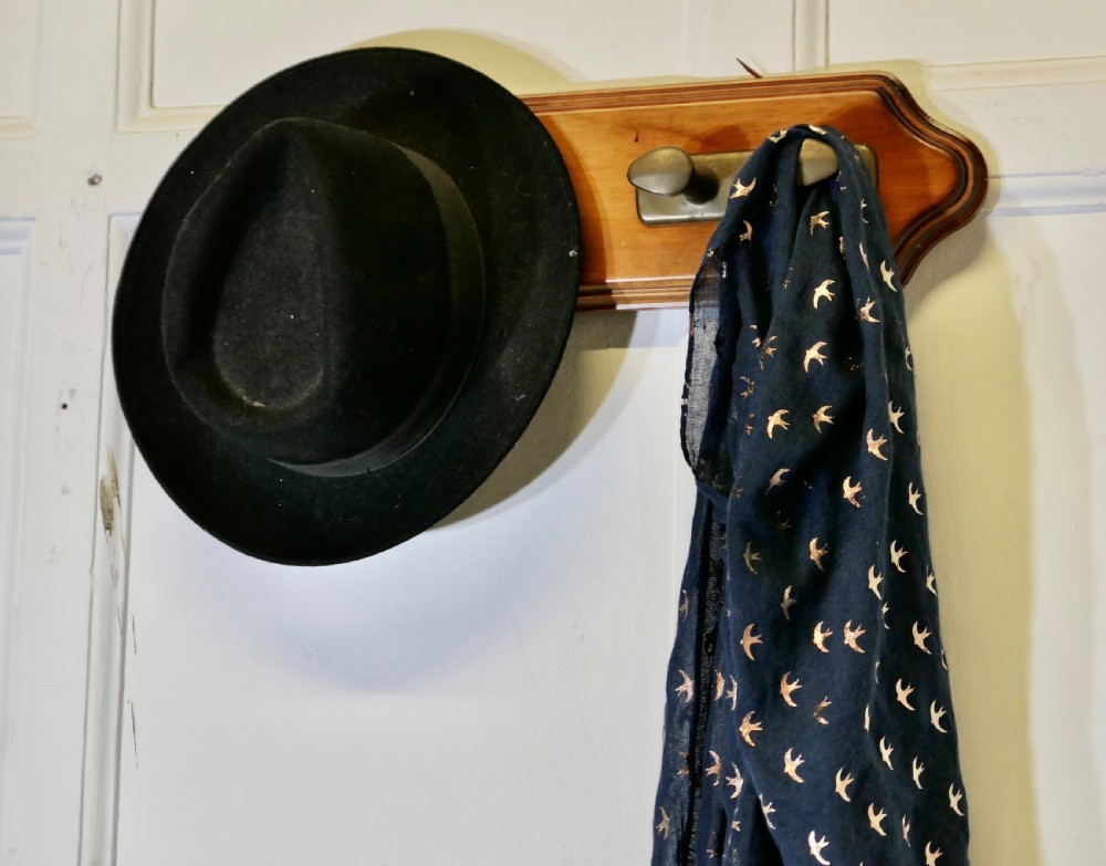 A wall-mounted shaped wooden backboard fitted with two pairs of smooth bronze nautical cleat hooks. View V