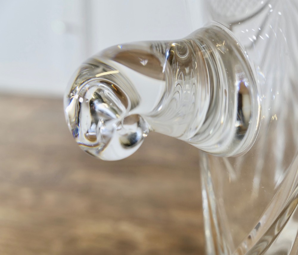 A heavy clear cut crystal champagne ice bucket featuring geometric drapery cuts, two applied scroll handles, and a stepped circular base. View V
