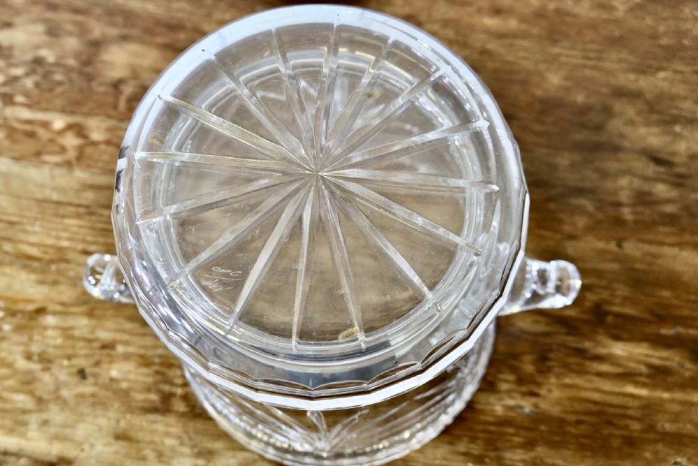 A heavy clear cut crystal champagne ice bucket featuring geometric drapery cuts, two applied scroll handles, and a stepped circular base. View VI