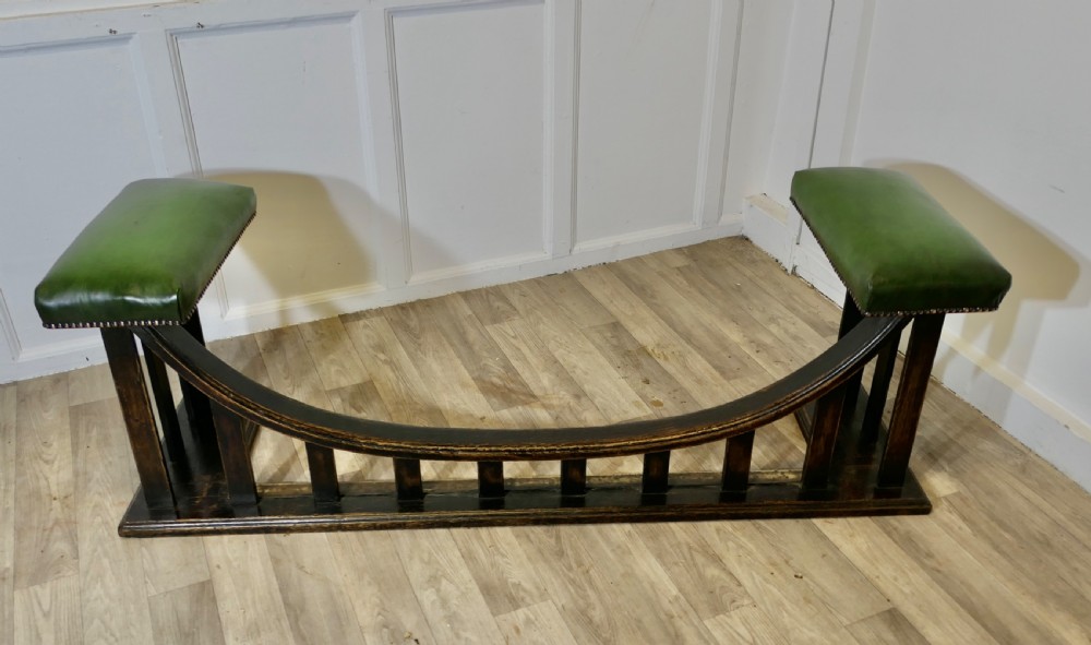 An Arts and Crafts dark oak club fender featuring two green leather upholstered seats with brass studding above vertical timber slats. View III